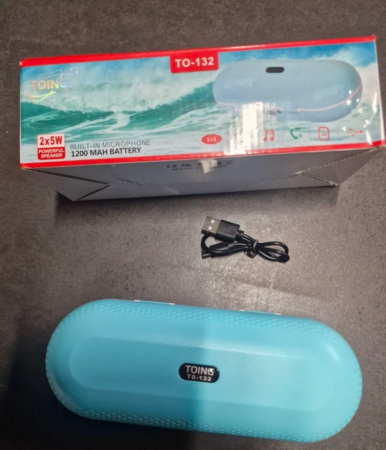 altifalante Bluetooth portátil Toing TO-132, apresentado numa caixa azul claro.